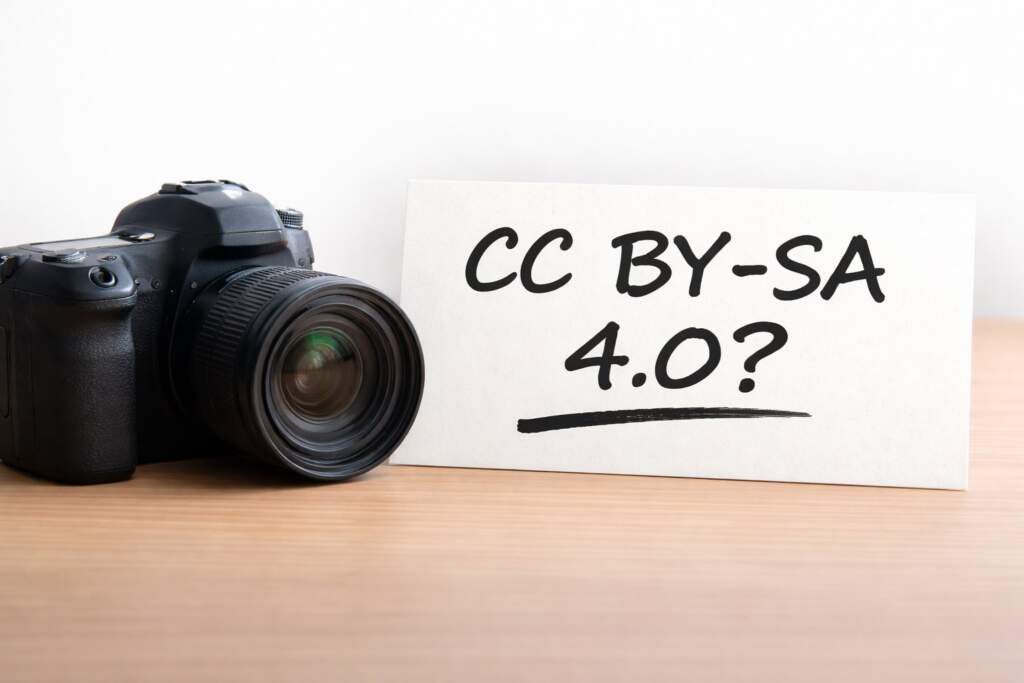 Kamera neben Karte mit der Aufschrift „CC BY-SA 4.0?“ zum Thema Creative-Commons-Lizenz in der Fotografie Symbolbild